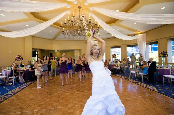 Bride tossing bouquet at wedding reception.
