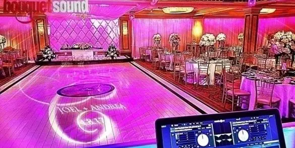 Elegant pink-lit wedding reception ballroom with dance floor.