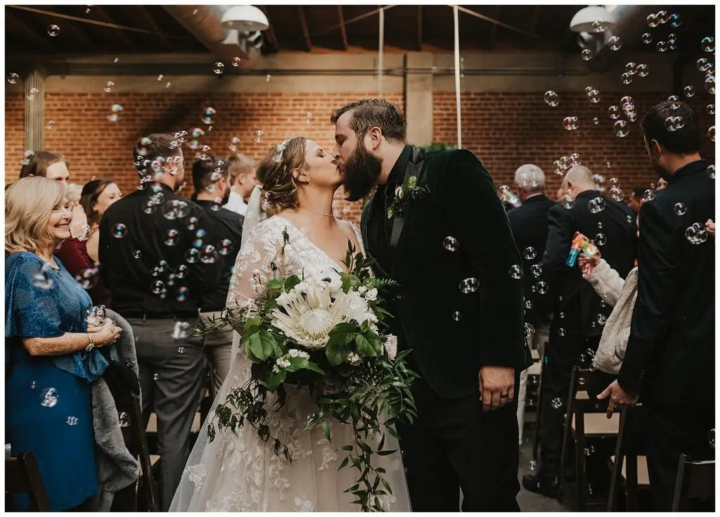 Bride and groom kissing at wedding with bubbles.