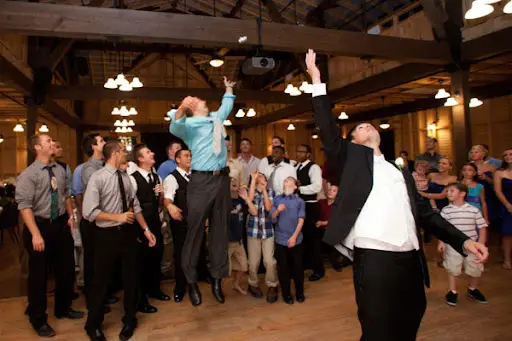Guests catch garter belt at lively wedding reception.