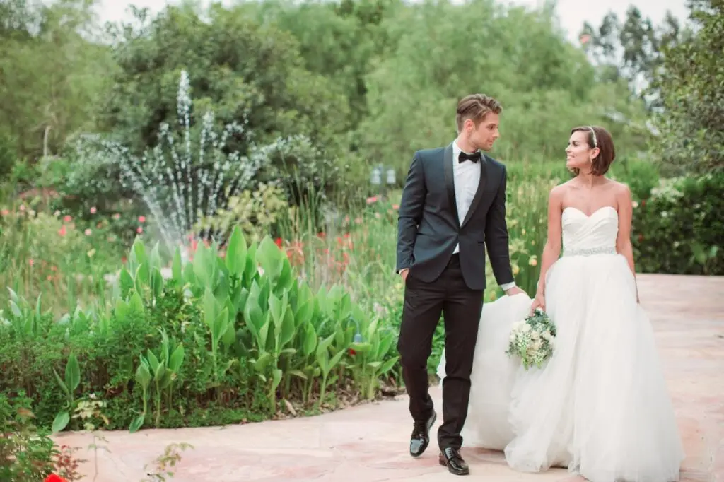Bride and groom walking in garden.