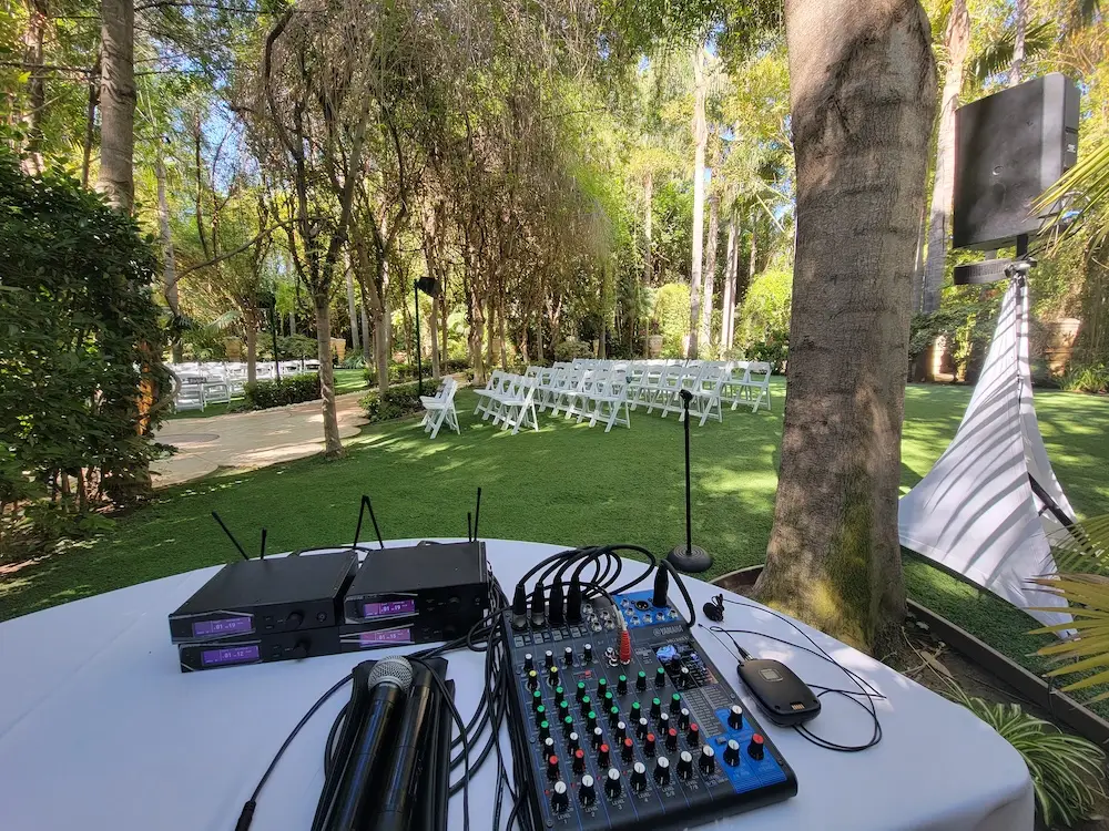 Outdoor wedding setup with audio equipment on table.