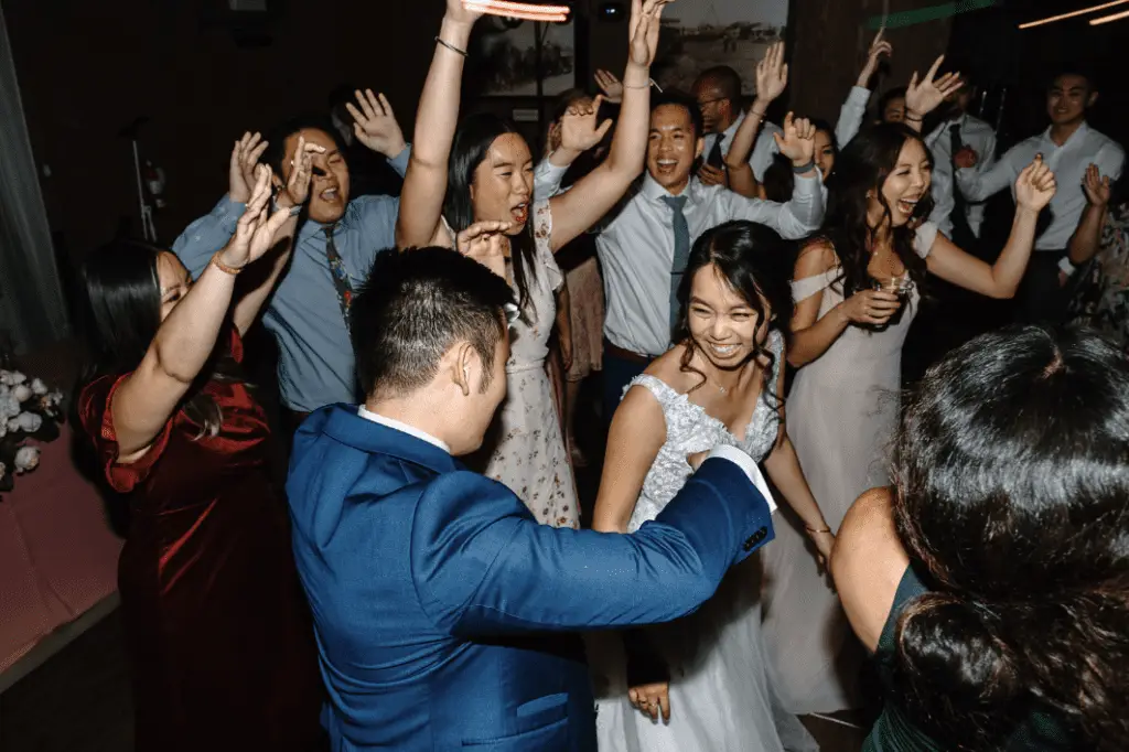 Happy wedding guests dancing energetically at reception.