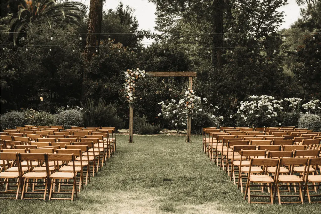 Outdoor wedding venue with wooden chairs and floral arch