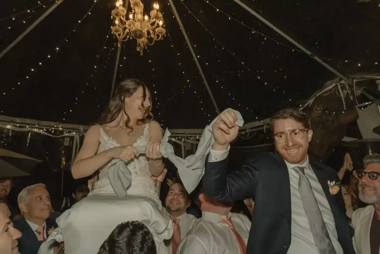 Bride and groom lifted during wedding celebration.